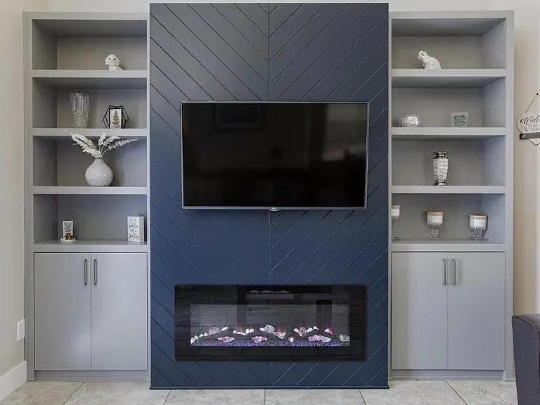 Built-in media wall with mounted TV, electric fireplace, and display shelving plus closed storage for easy organization.
