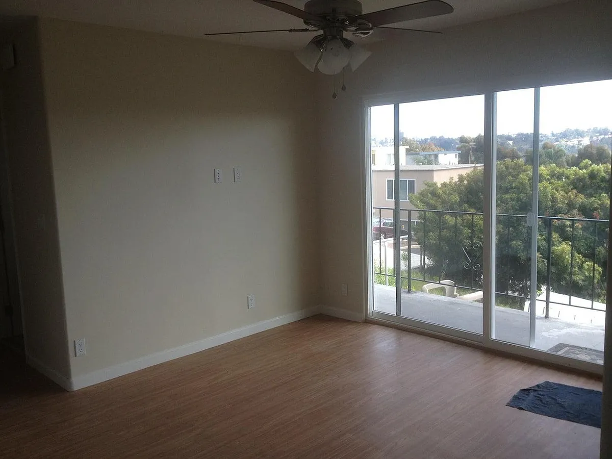 living room with sliding glass door; plenty of natural light from south facing balcony; easy-to-clean laminate floors - 5937 Mildred St