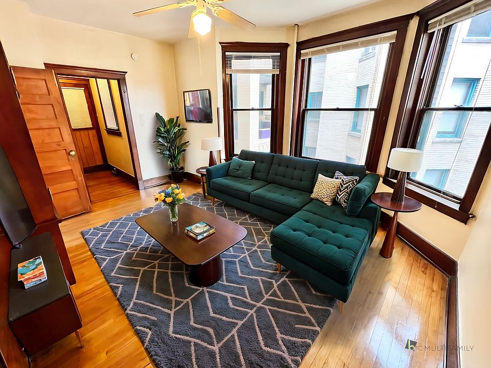 Charming and cozy living room with elegant hardwood floors, plush leather seating, and a modern entertainment center.