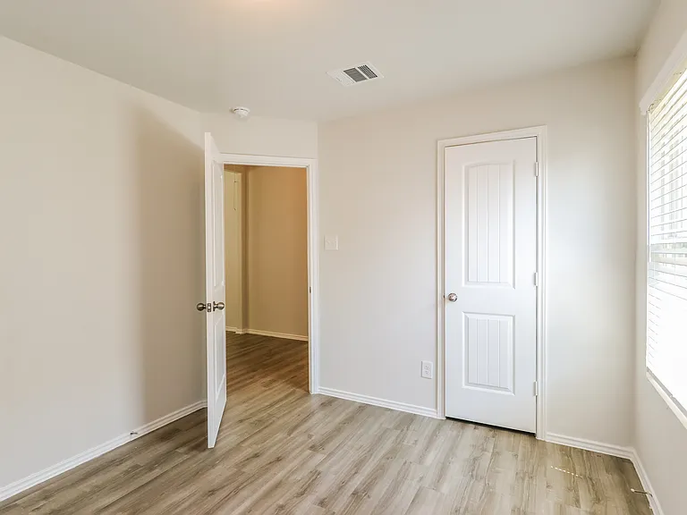Bright and airy room with elegant wooden flooring, ample natural light, and a modern door design. Bright and airy room with elegant wooden flooring, ample natural light, and a modern door design.
