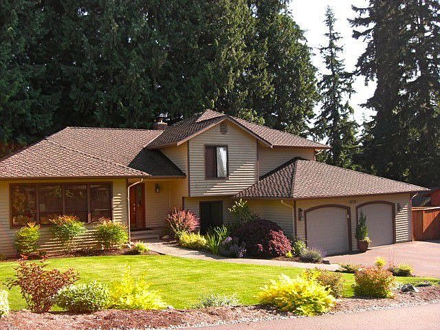 Front of home with newer roof, beautiful landscaping, sprinkler system and RV parking to the right o