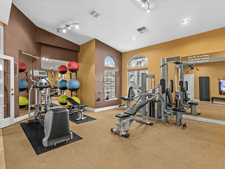 Fully equipped fitness center featuring cardio machines, strength equipment, and open workout space.