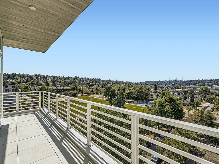 Enjoy breathtaking city views from the spacious balcony at Anker Ballard, featuring a modern railing and ample space for relaxation.