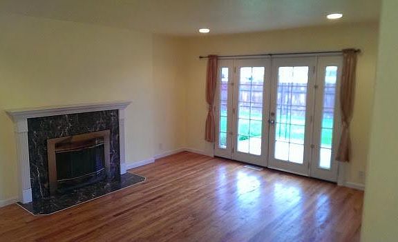 Living room with wood fireplace and french doors to backyard patio