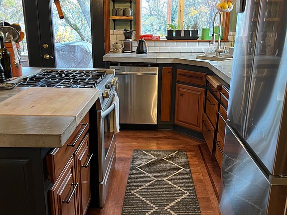 The kitchen is small but mighty. Renovated in 2023. Gas stove. Cool concrete countertops. Two built-in Boos Block cutting boards. Live edge shelving. Views of the river while you do dishes.