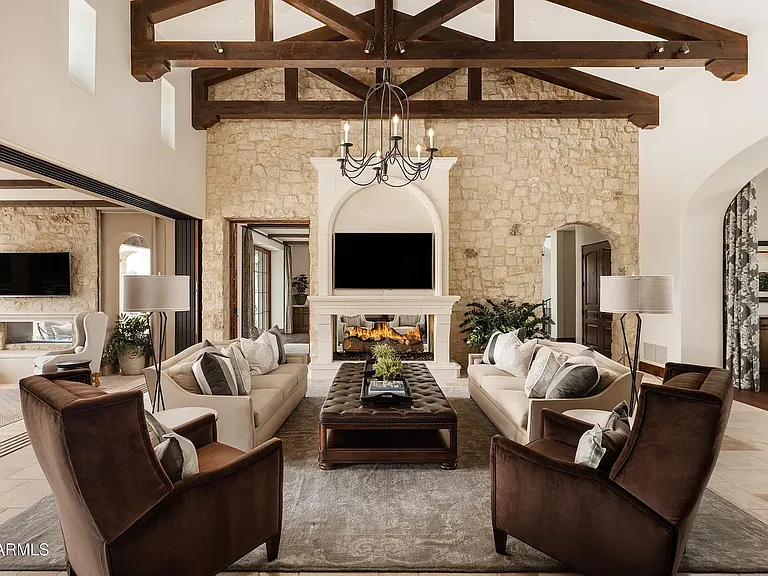 Beautifully appointed living room with vaulted ceilings, rich wood beams, and a striking stone fireplace.