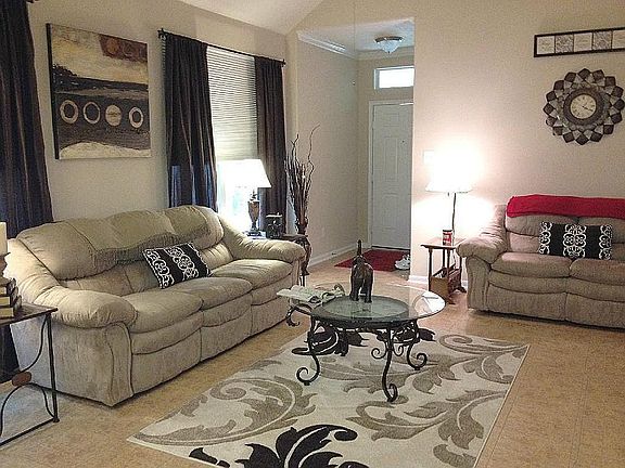 Spacious living room area with tile floors, gas log fireplace and high ceilings.
