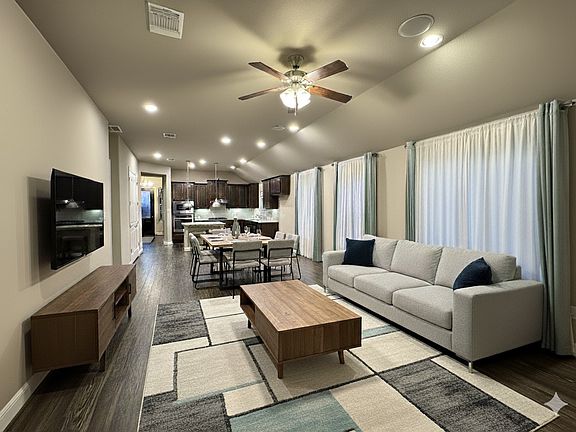 Bright open-concept living area with modern furniture, recessed lighting, and a seamless flow into the dining and kitchen spaces.