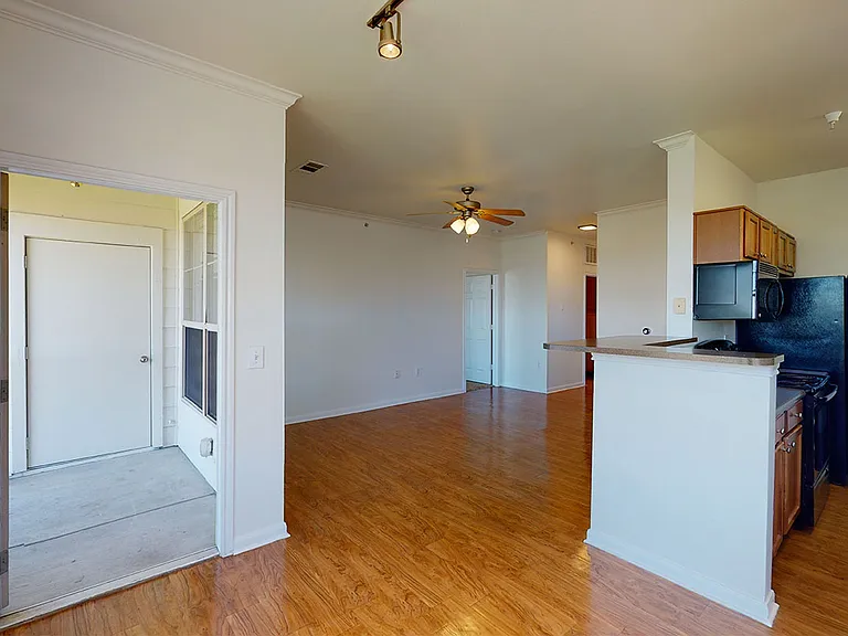 Apartment kitchen, dining and living room with wood-style flooring.