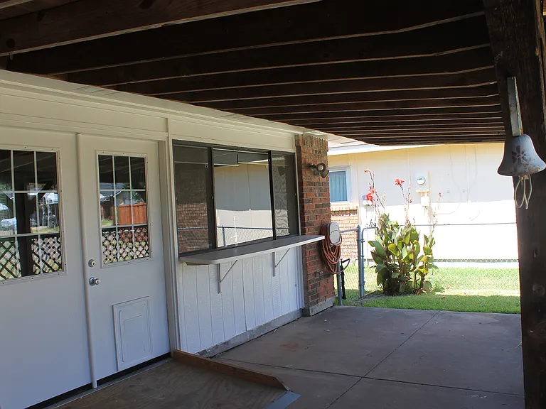 A double door leads to a covered patio with a convenient outdoor bar area. A ramp provides easy accessibility
