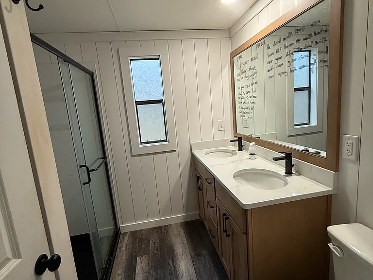 Master bath with double sinks and walk-in shower and linen storage behind door
