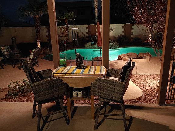 Pool with waterfall, seating area and a fire pit on the outside.