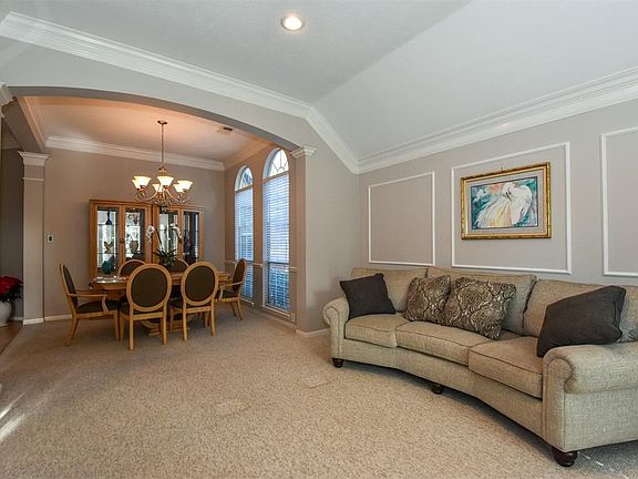 The living room flows seamlessly into the formal dining enhanced with double crown molding, archways and neutral paint colors.