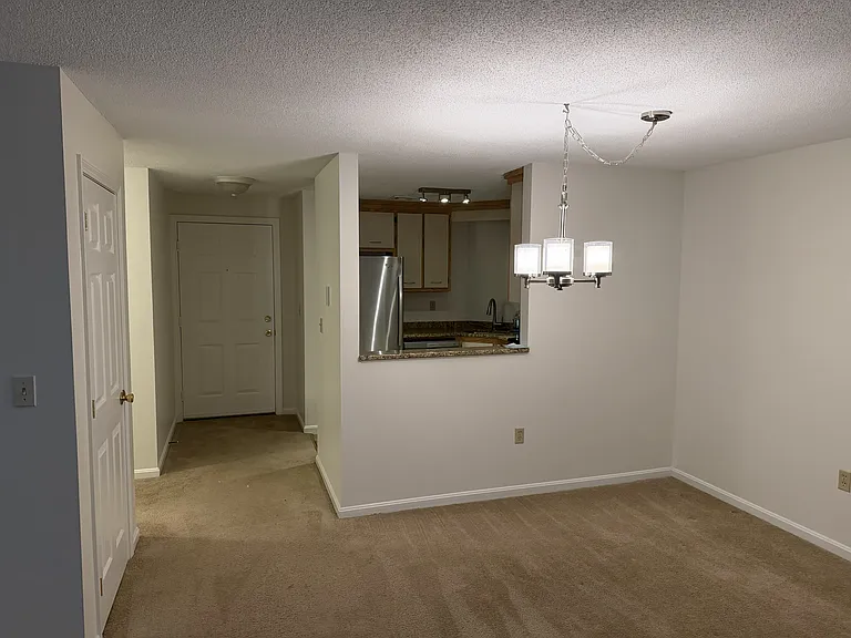 Looking at the dining area, into the kitchen, and the hallway to the entrance. On the left is the coat closet, just beyond that is a hallway.