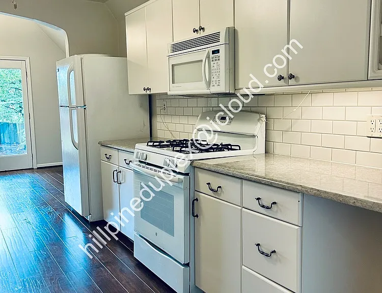 Spacious kitchen quartz counter tops with gas stove, built-in microwave, fridge, dishwasher, garbage disposal, and pantry