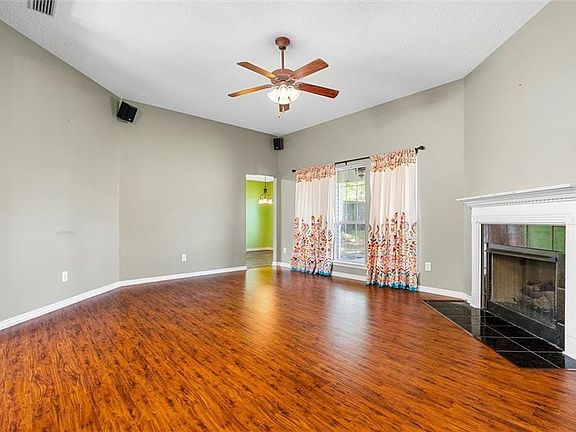 Unfurnished living room with wood finished floors, ceiling fan, a fireplace, and baseboards