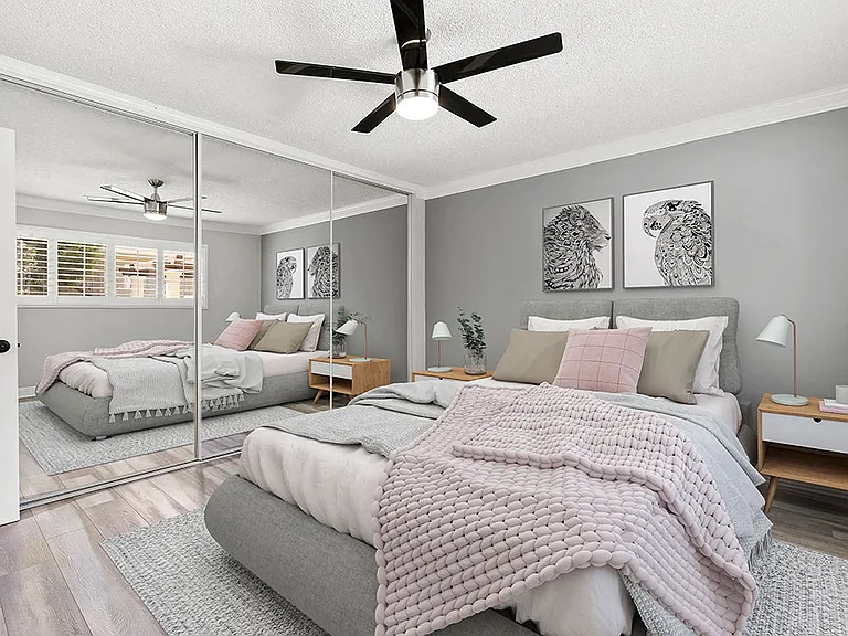 Carpeted bedroom with ceiling fan and large mirrored closet.