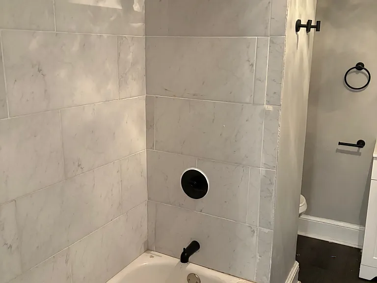 Shower/Tub Combination w/ Tiled Backsplash. New Shower Head, Shower Rod, Towel Hooks and Tub Fixtires.