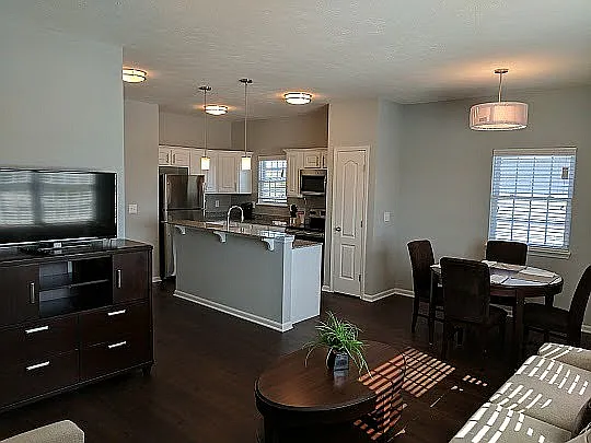 A look inside the furnished model apartment at Hamilton Station, featuring an open-concept design that connects the living room, dining space, and kitchen _ with a stylish island and breakfast bar combo anchoring the space.