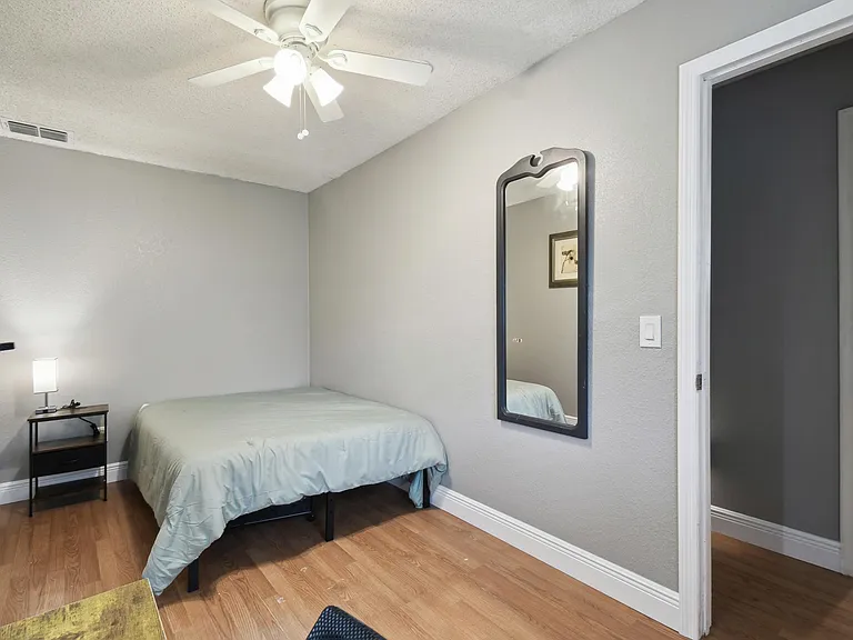 Full size cozy bed, with end table, light and storage container under the bed.