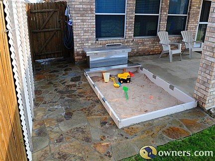 Large sand box with lid and surrounding patio.