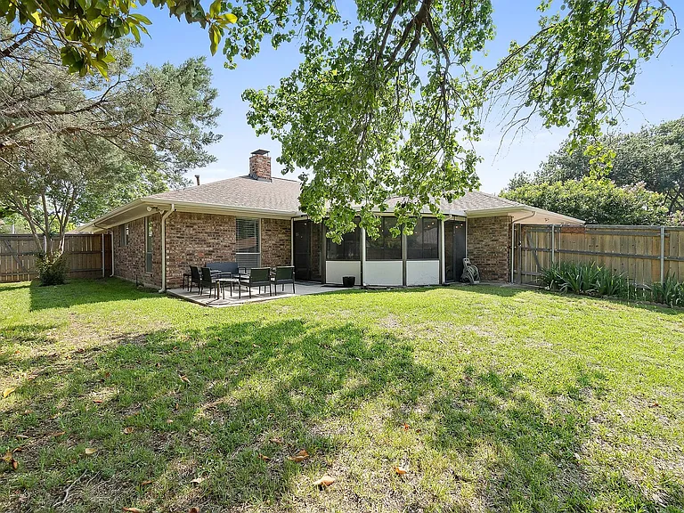 Back of house with brick siding, a chimney, a fenced backyard, and a sunroom