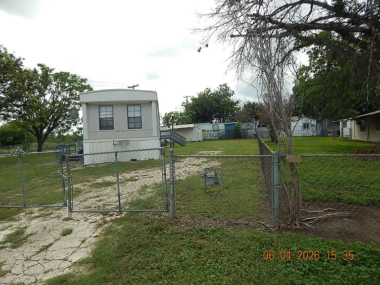 View from main property entrance - showing front of home = stone driveway - shade trees on the left