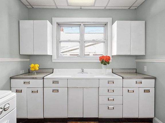 Charming retro kitchen features a gas range and huge farmhouse sink overlooking an exterior window.