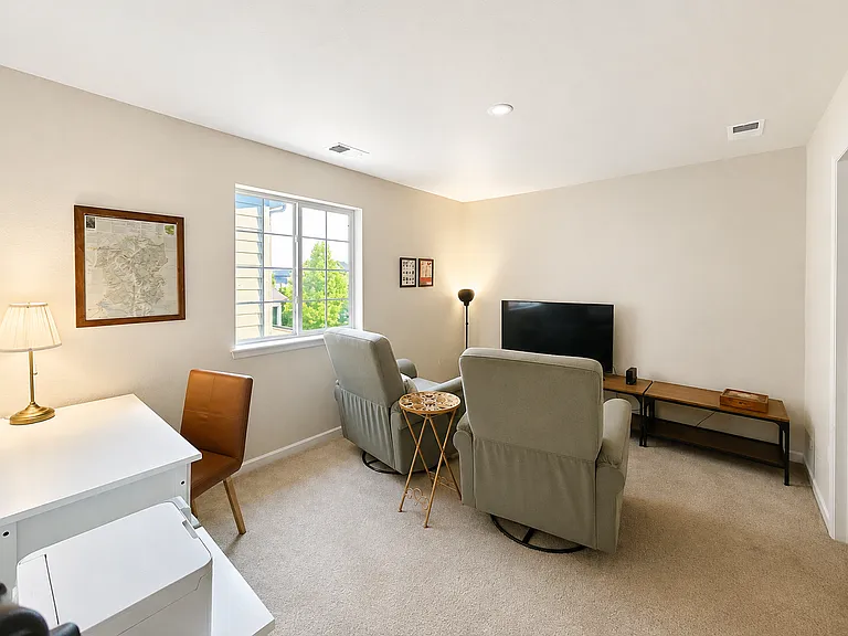 Furnished upstairs lounge featuring TV seating, work desk, printer, and plenty of natural light.