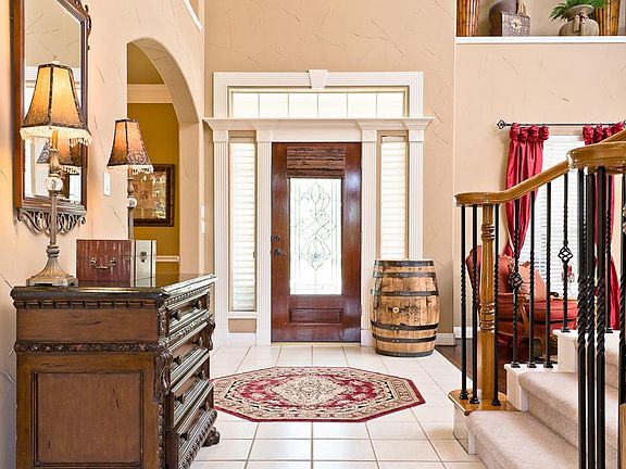 Another view of the foyer highlighting the beautiful leaded glass front door with roman shade, two side lights and a transom. A coat closet and powder room are nearby.