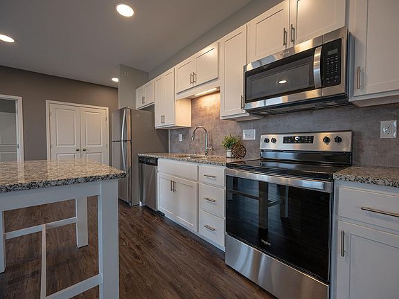 A modern kitchen: Granite countertops, stainless steel appliances, white cabinets, and over-the-stove microwave/range hood