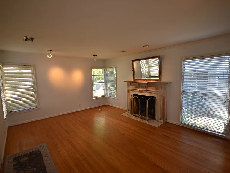 Hardwood flooring throughout, featuring a fireplace with a stone mantel and hearth.