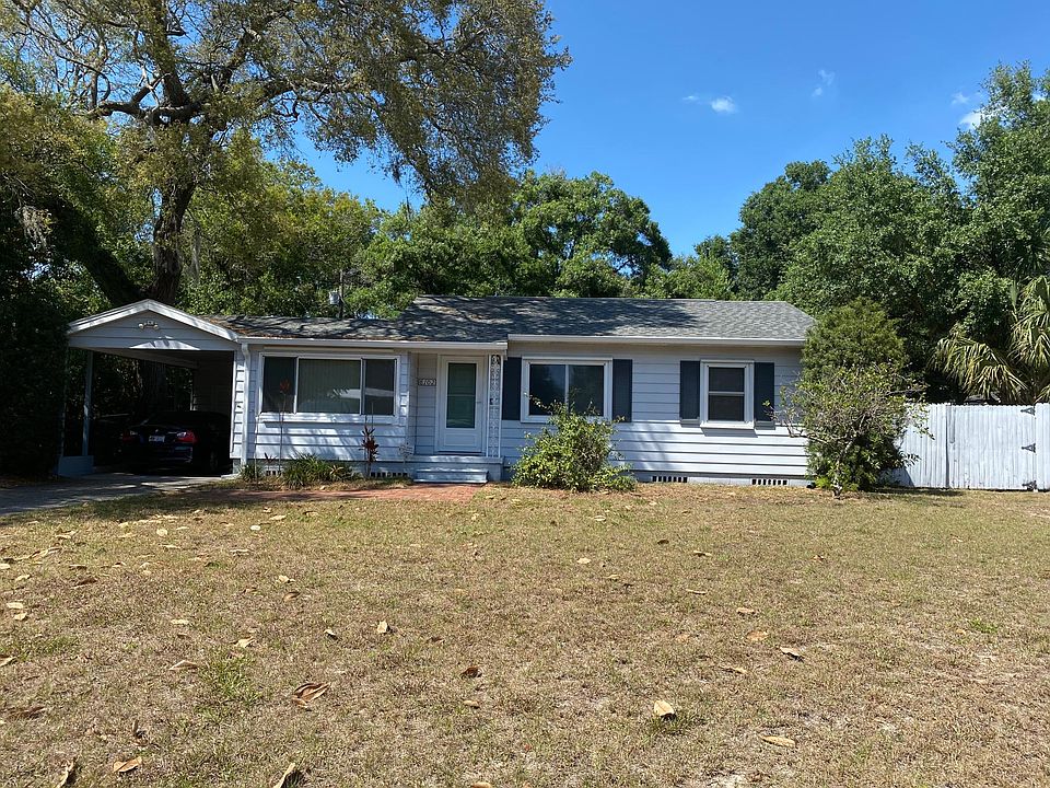 Front of home with huge yard, long driveway, and covered carport