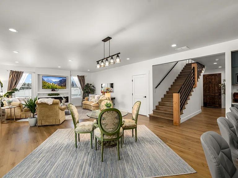 Bright and inviting living and dining area featuring modern lighting, an elegant stairway design, and a warm Montana-inspired atmosphere perfect for gathering, relaxing, and entertaining.