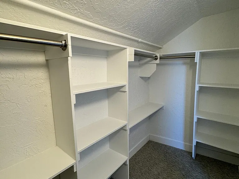 Another view of the spacious primary walk-in closet with extensive built-in shelving and storage.