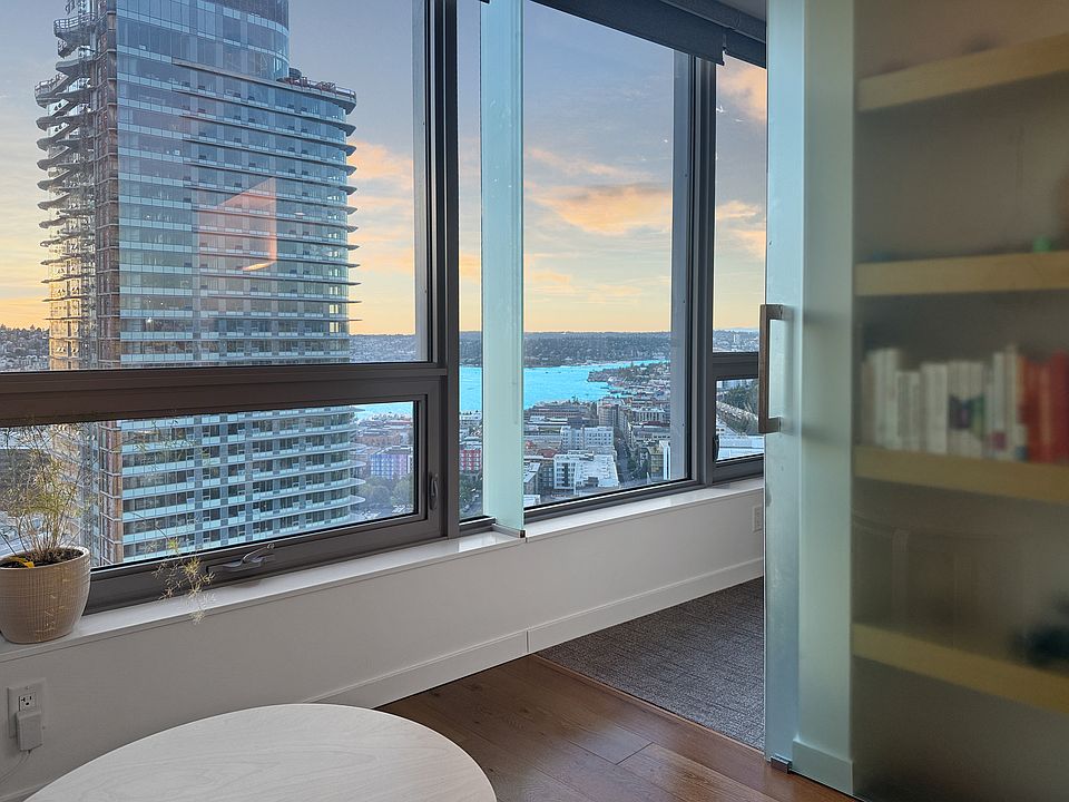 Breathtaking Lake Union views from your living room! Large windows frame a dynamic panorama of water, city, and mountains, creating an inspiring backdrop for relaxation and urban living.