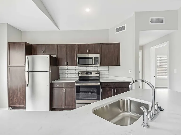 Upgraded kitchens with pull-down faucet, sleek wood cabinetry, and quartz countertops.