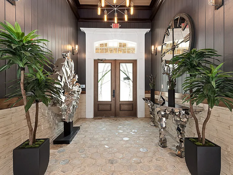 Chic entrance with modern geometric decor, lush potted plants, and unique art features, exuding elegance and style.