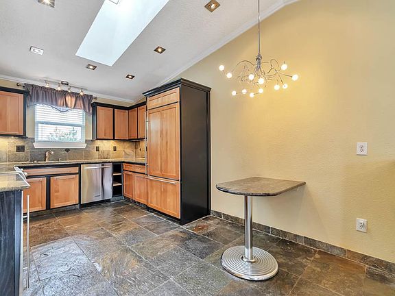 VIEW OF COZY BREAKFAST NOOK WITH BUILT-IN GRANITE TABLE & MODERN CUSTOM CHANDELIER RIGHT ABOVE IT