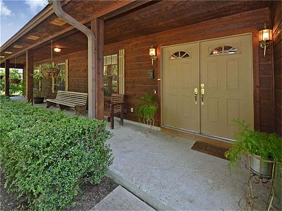 A long covered front porch adds to the tranquil setting and double doors enter into the house.