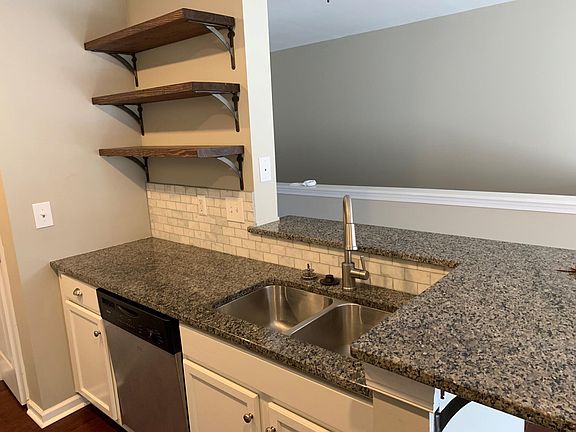 Open shelving and granite counter tops in kitchen with bar