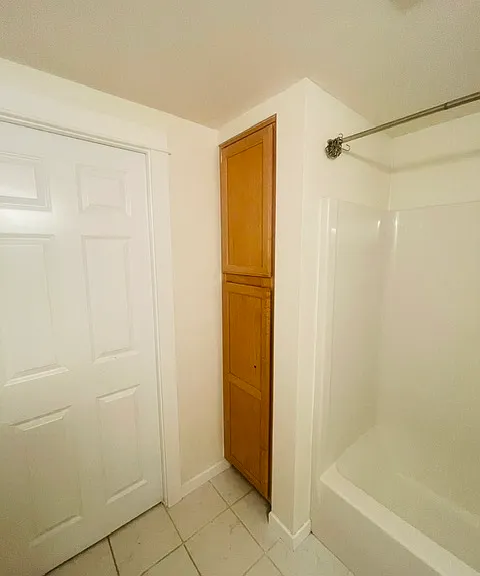 large storage cabinet in bathroom. Doors provide access to on-suite bedroom and another door to the living room.