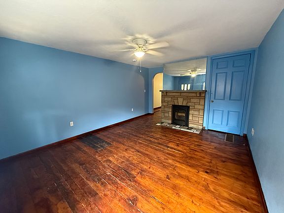Front room, includes first floor gas fireplace and ceiling fan. Includes original hardwood flooring.