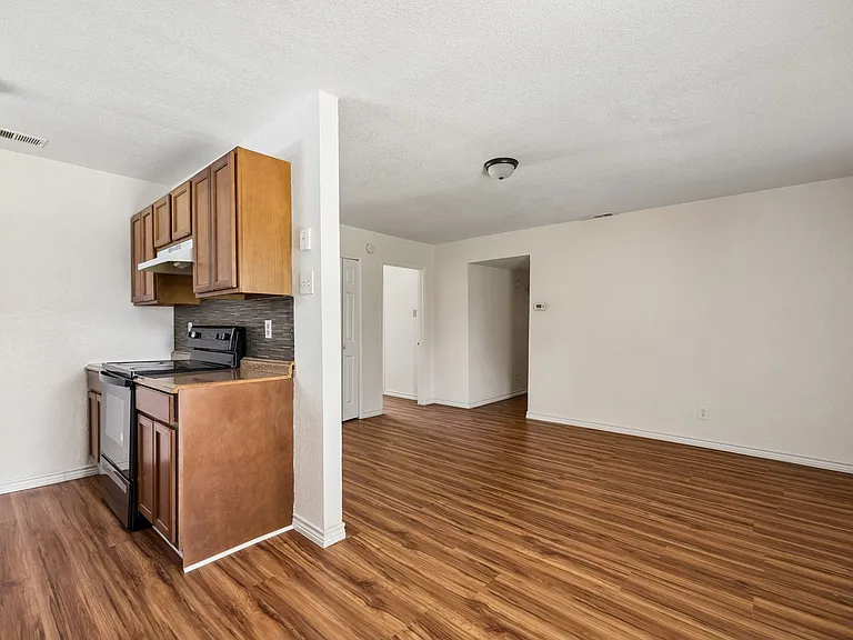 Kitchenette with wood-finish cabinetry, dark countertop, and a tiled backsplash