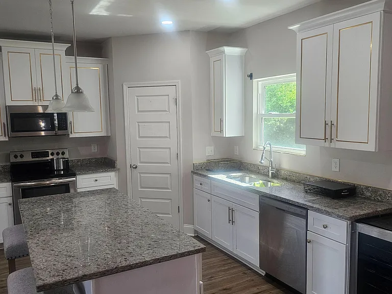 Spacious kitchen with granite counters, ample cabinetry, stainless appliances, and an island for extra prep and seating.