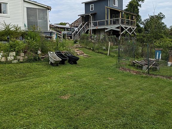 view of the back of the house/sun room. In background are fenced in gardens/chicken run and owner's tiny house.