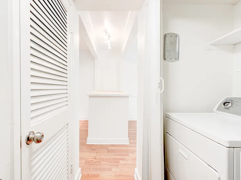 Hallway leading to 1/2 bath storage cabinet and washer dryer