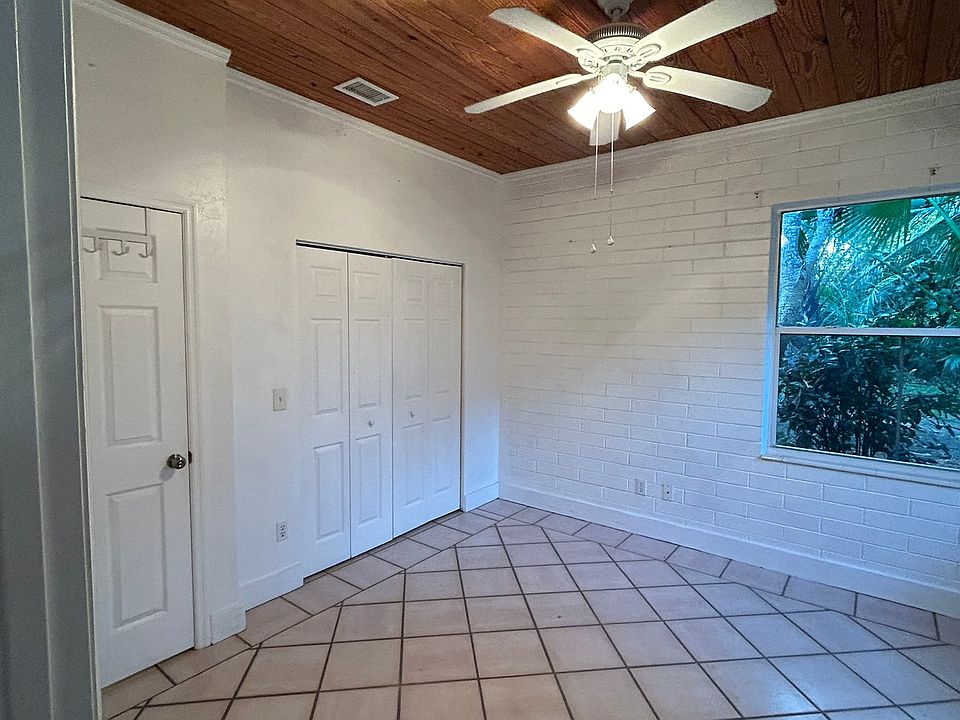 Bedroom with high ceilings, one closet, and two large windows looking out to tropical landscape and private back yard area (not fenced). New blinds are currently being installed.