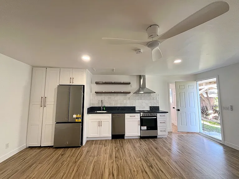 Kitchen. Main door on the right. Door to bedroom partly covered by open front door.
Washer and dryer are in the far left cabinet.