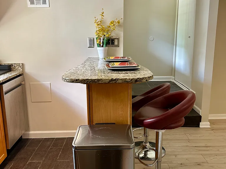 Full kitchen with granite countertops and bar stools for dining.